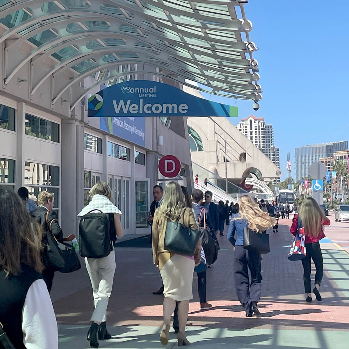 people walking under welcome sign to annual meeting