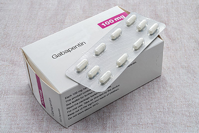 White box of gabapentin capsules with a blister pack of 10 white capsules resting on top
