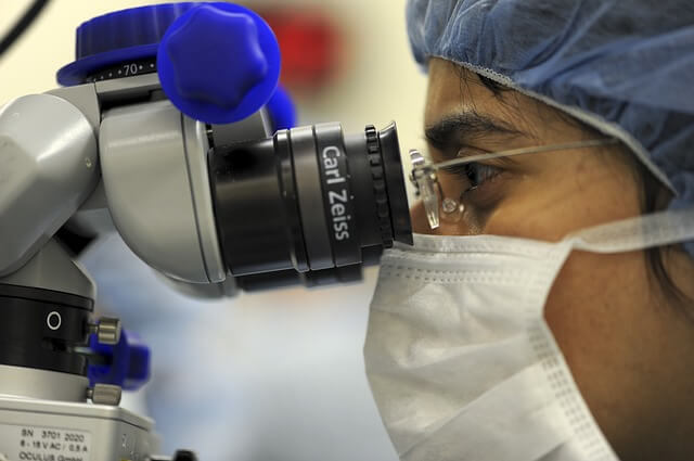 researcher looking through microscope